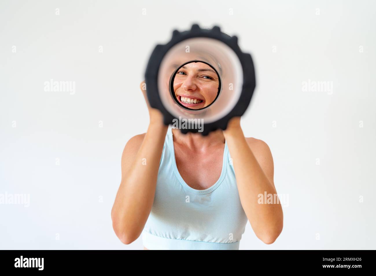 Sporty female person looking through foam roller and has fun. Foto Stock