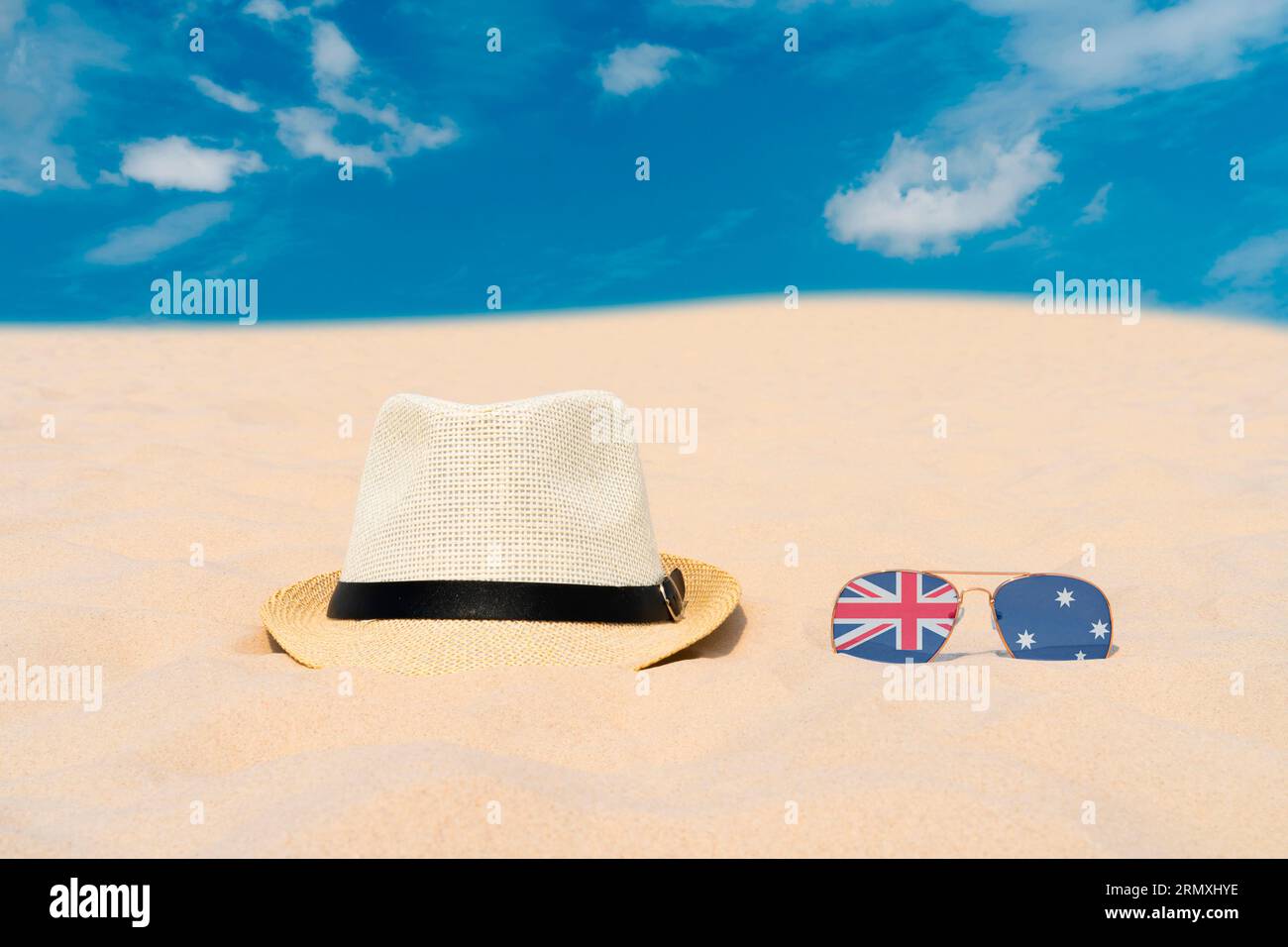 Gli occhiali da sole con occhiali sotto forma di bandiera dell'Australia e un cappello giacciono sulla sabbia contro il cielo blu. Concetto di vacanze estive e viaggi in Australia Foto Stock
