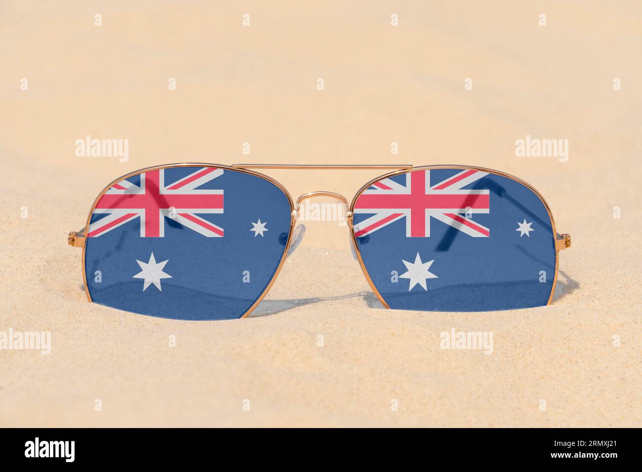 Gli occhiali da sole con occhiali in forma di bandiera dell'Australia giacciono sulla sabbia. Concetto di vacanze estive e viaggi in Australia. Riposo estivo. Stagione natalizia Foto Stock