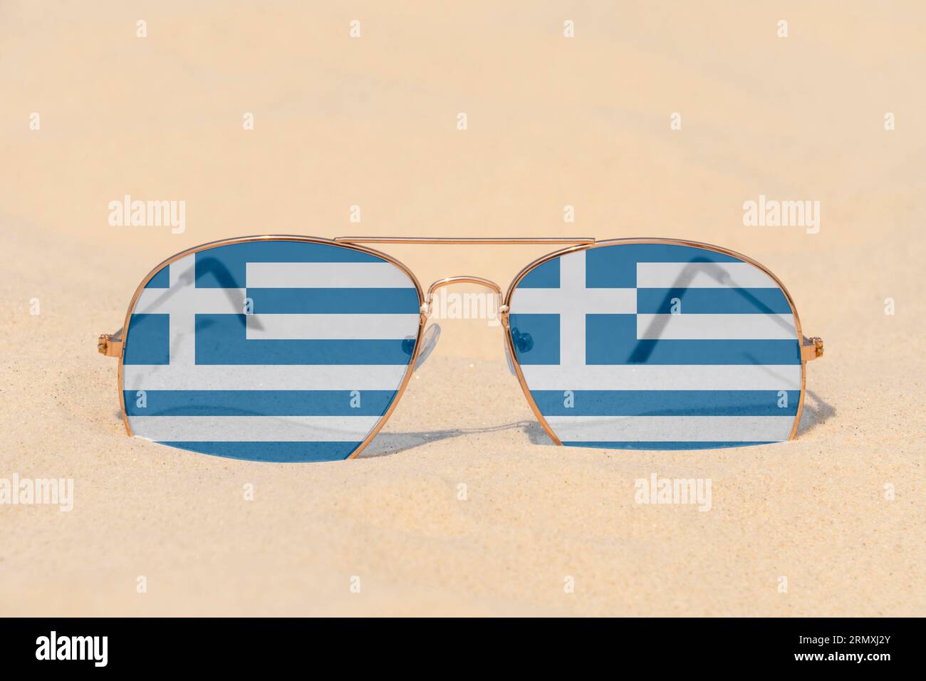Gli occhiali da sole con occhiali sotto forma di bandiera della Grecia giacciono sulla sabbia. Concetto di vacanze estive e viaggi in Grecia. Riposo estivo. Stagione natalizia Foto Stock