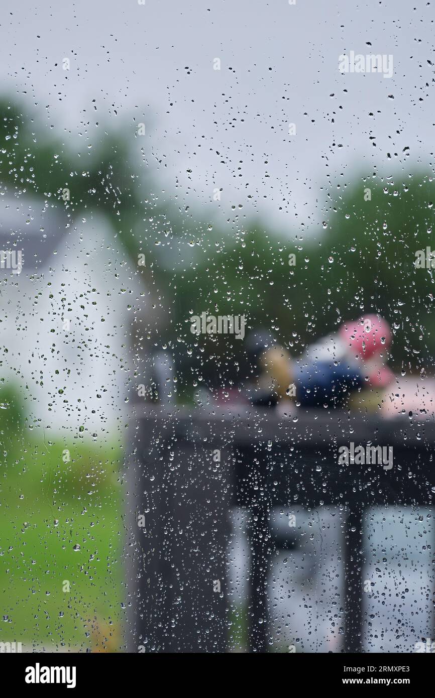 Vista all'esterno in una giornata di pioggia con gocce d'acqua sulla finestra. Foto Stock