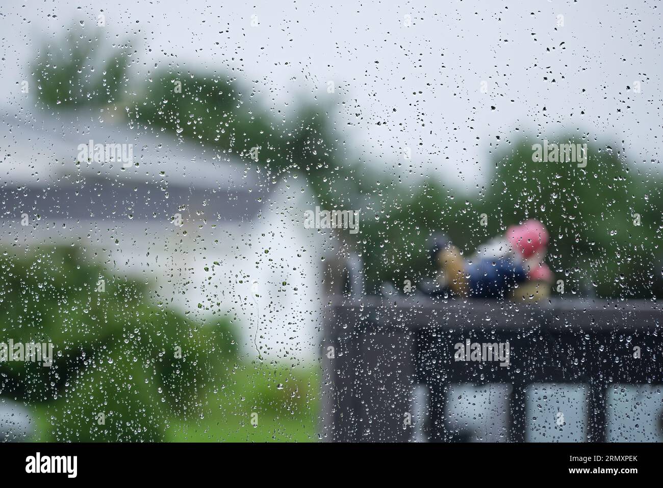 Vista all'esterno in una giornata di pioggia con gocce d'acqua sulla finestra. Foto Stock