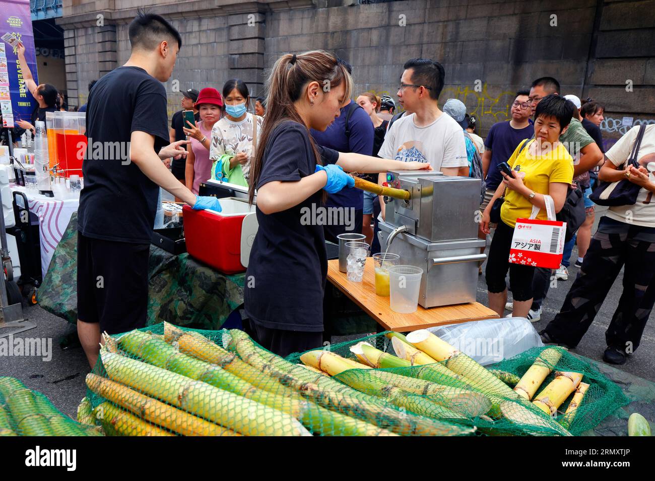 Un fornitore di succo di canna da zucchero Daddy sputa un bastone di canna da zucchero a pensare! Evento del mercato notturno di Chinatown a Manhattan Chinatown, New York, 23 luglio 2023. Foto Stock