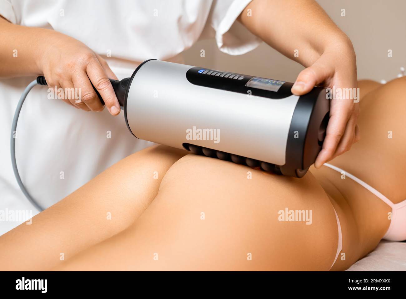 Lo specialista utilizza un dispositivo professionale per bruciare i grassi per eseguire un massaggio addominale con esperienza Foto Stock