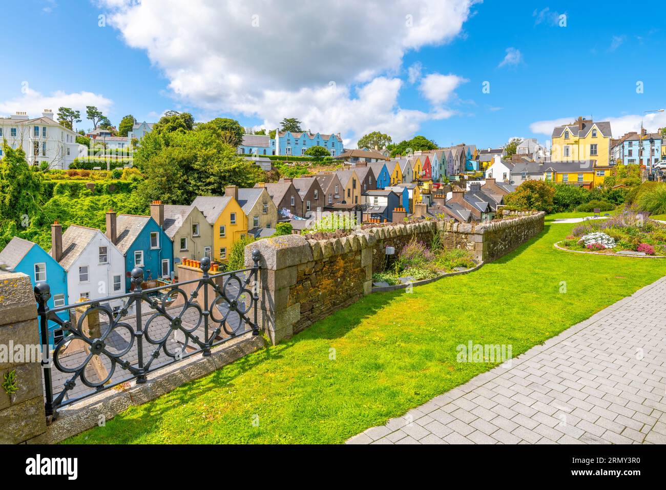 Il pittoresco e colorato Deck of Cards, una fila di case cittadine dipinte con colori vivaci, viste dal parco Garden of Reflection di Cobh, Irlanda. Foto Stock