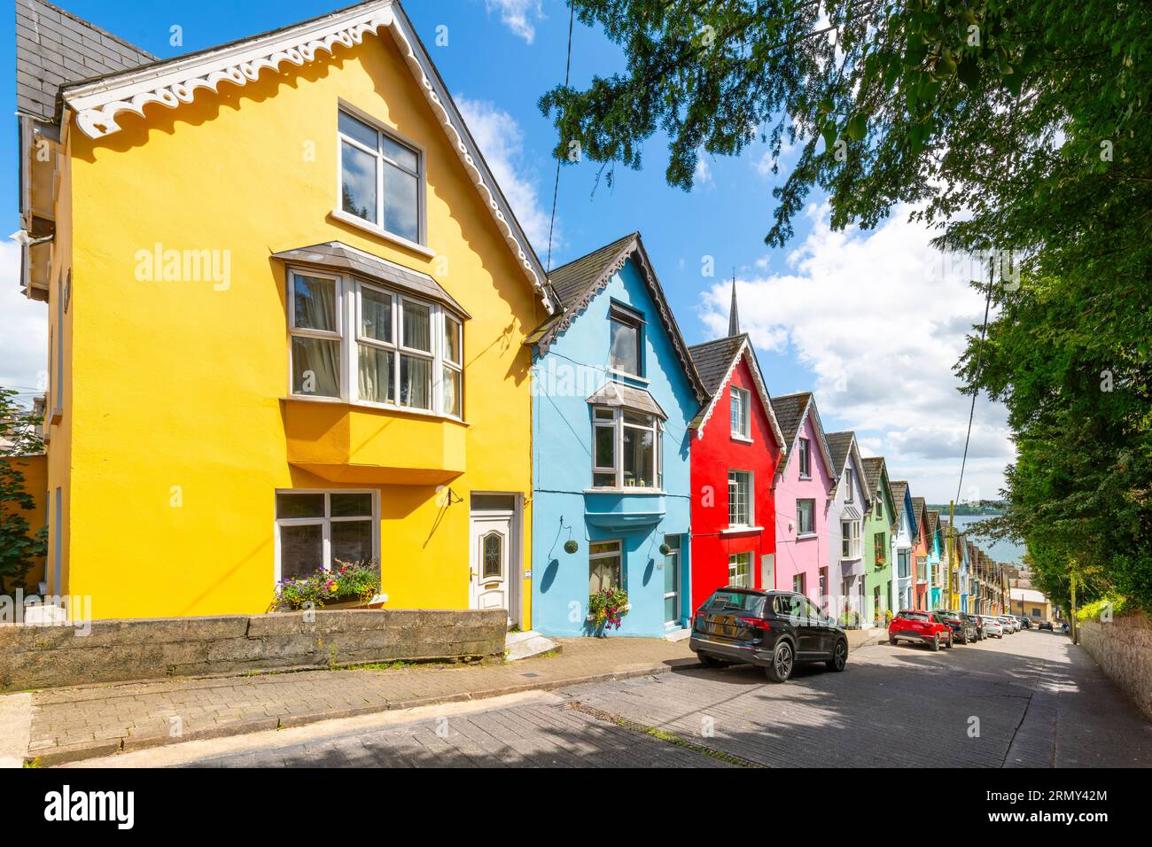 Il pittoresco e colorato Deck of Cards, una fila di case cittadine dipinte con colori vivaci, viste dal parco Garden of Reflection di Cobh, Irlanda. Foto Stock
