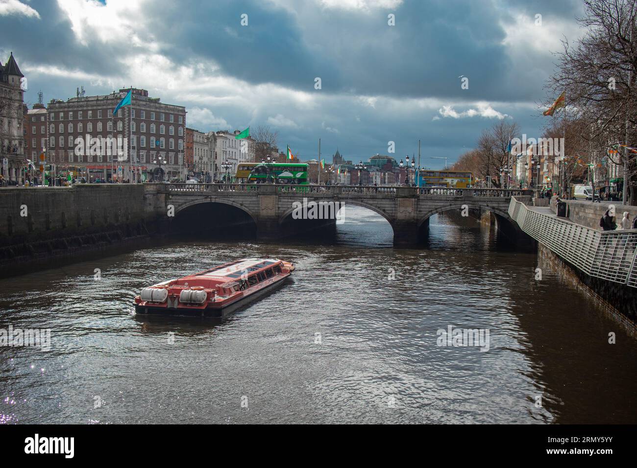 Centro di dublino con il fiume Liffey e una barca in una giornata nuvolosa e soleggiata. Guardando verso il ponte o'connel. Foto Stock