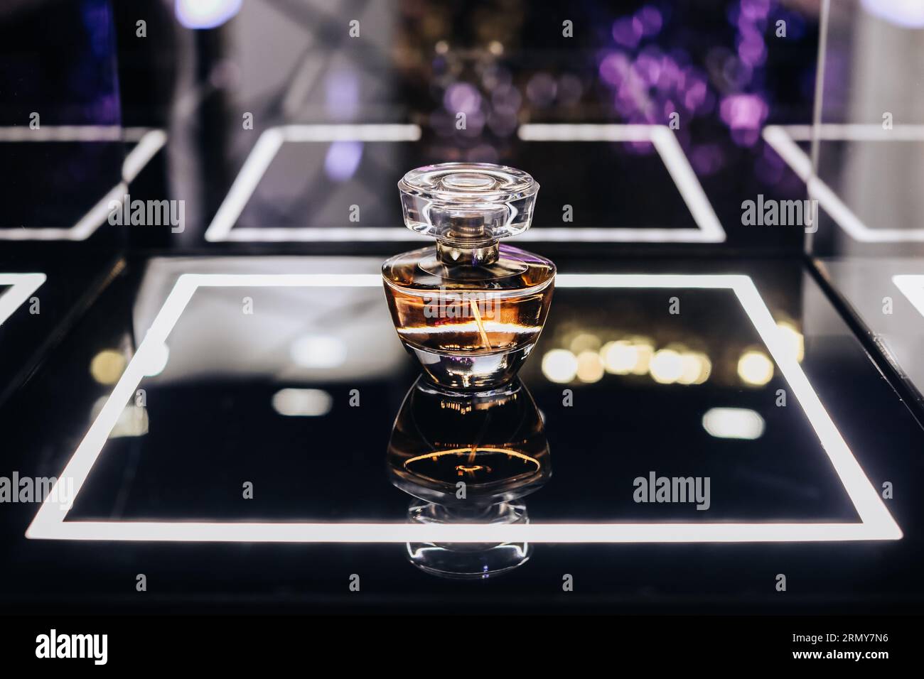 Bottiglia di profumo in vetro su un supporto a specchio. Boutique di profumeria di lusso. Copia spazio Foto Stock