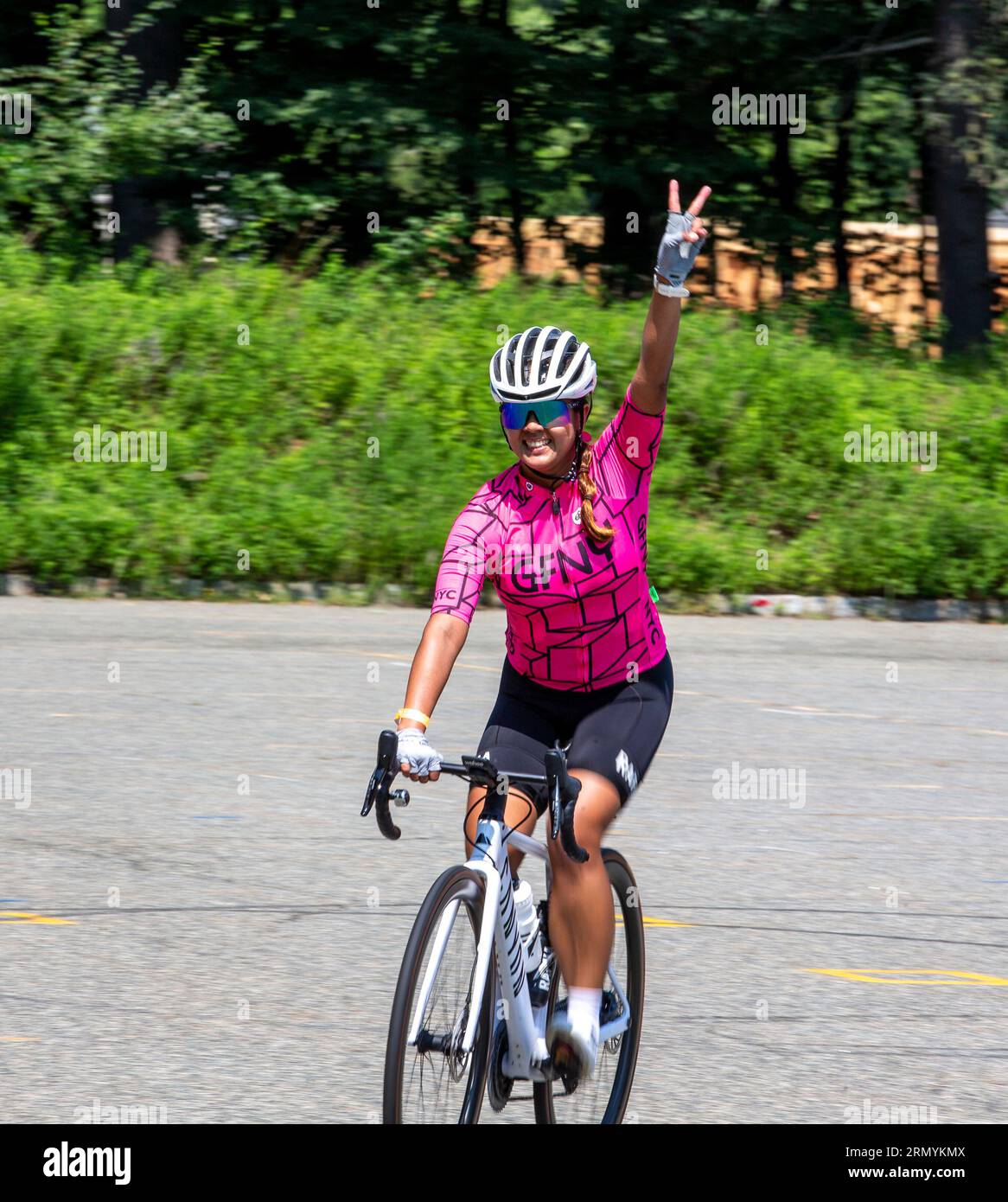 Ciclista femminile che mostra un segno di vittoria al completamento di un rally ciclistico Foto Stock