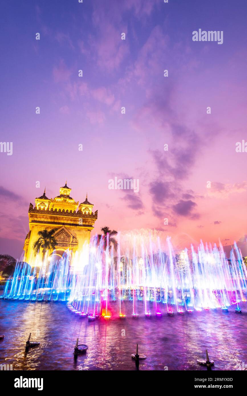Splendida luce colorata e fontana, sincronizzata con la musica laotiana patriottica degli altoparlanti vicini, il memoriale della guerra di Patuxay illuminato Foto Stock