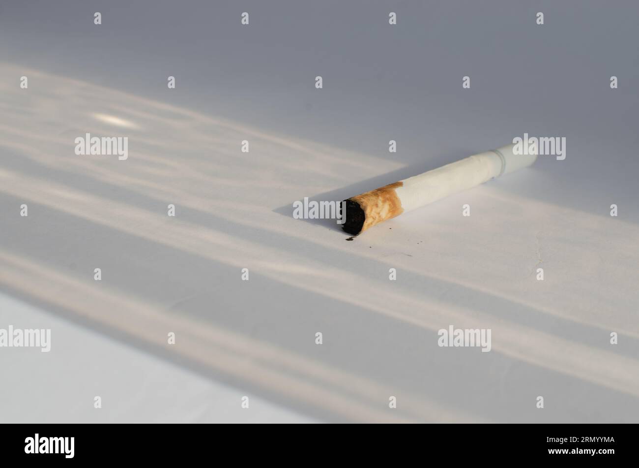 Dettaglio delle sigarette su una superficie bianca, che simboleggia i rischi per la salute e le malattie associate al fumo. Foto Stock
