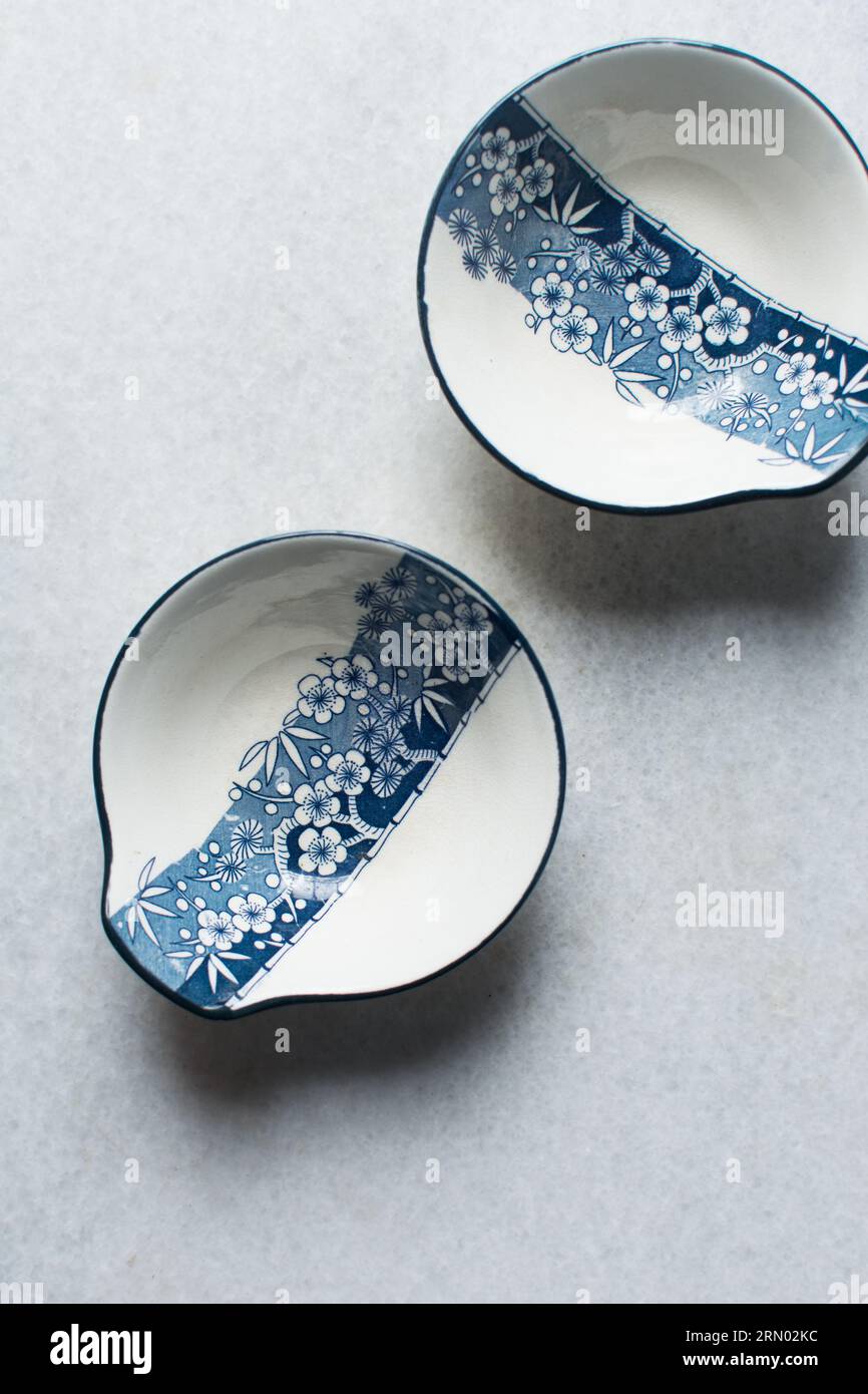 Ciotola in salsa tempura bianca e blu con motivo floreale, ciotola in salsa minimalista dipinta a mano, stoviglie in stile giapponese su uno sfondo minimalista Foto Stock