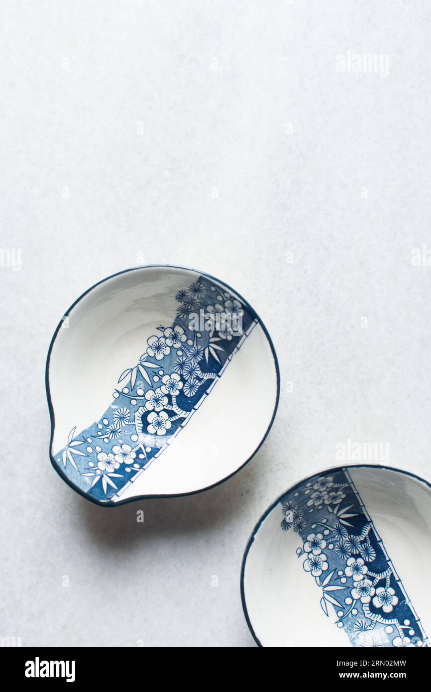 Ciotola in salsa tempura bianca e blu con motivo floreale, ciotola in salsa minimalista dipinta a mano, stoviglie in stile giapponese su uno sfondo minimalista Foto Stock