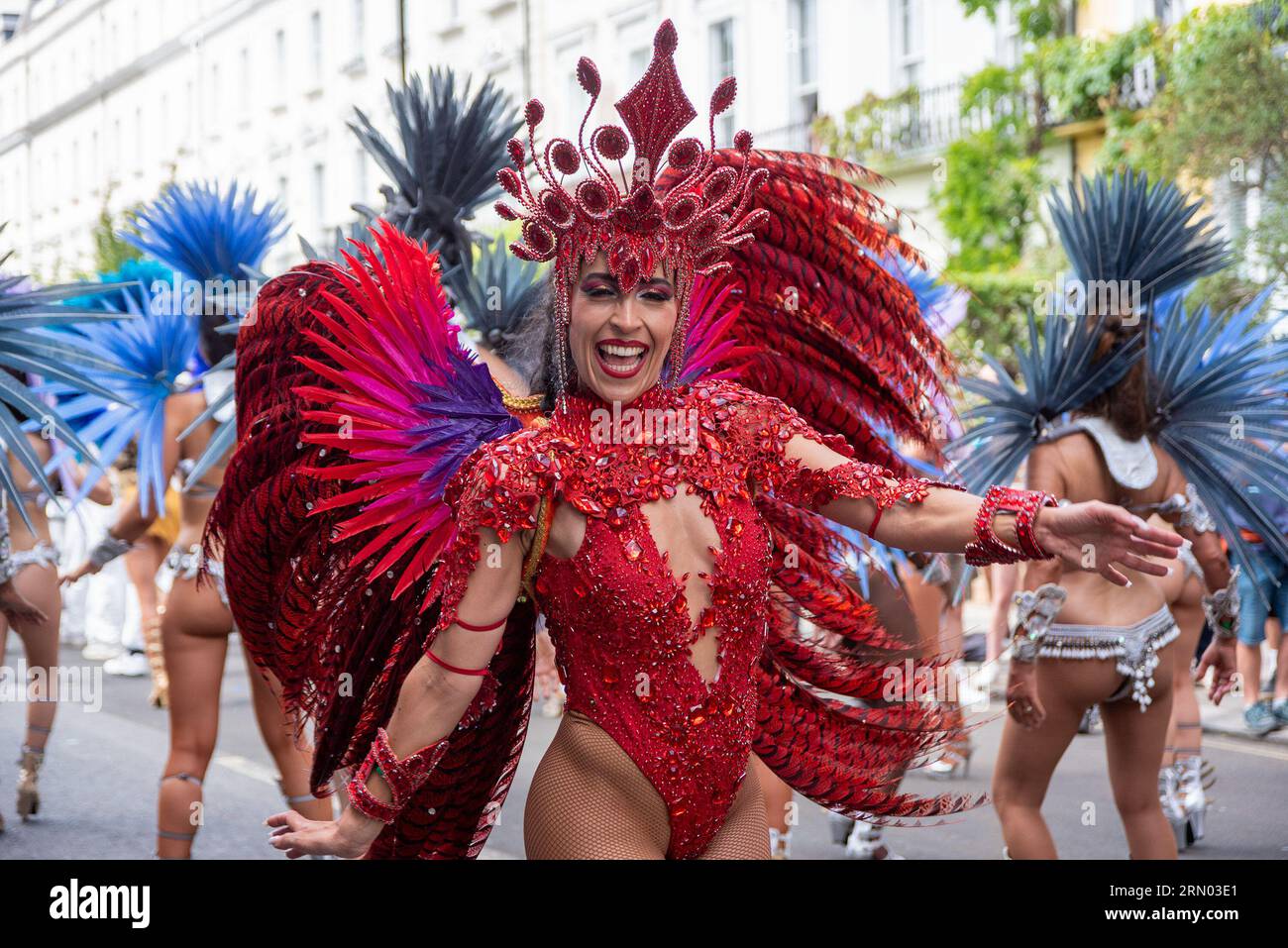 Una splendida ballerina di samba vestita con un costume colorato posa per una foto durante la sfilata del Carnevale di Notting Hill a Londra. Il Carnevale di Notting Hill è uno dei più grandi festival di strada del mondo. È iniziato nel 1966, ma ha avuto origine con il Carnevale caraibico organizzato nel 1959 con la comunità di immigrati da Trinidad e Tobago. Quest'anno il Carnevale di Notting Hill segna il 50° anniversario dell'introduzione dei sistemi audio e delle band Mas. Inoltre segna il 75° anniversario dell'arrivo dei passeggeri dell'Empire Windrush nel Regno Unito. Foto Stock