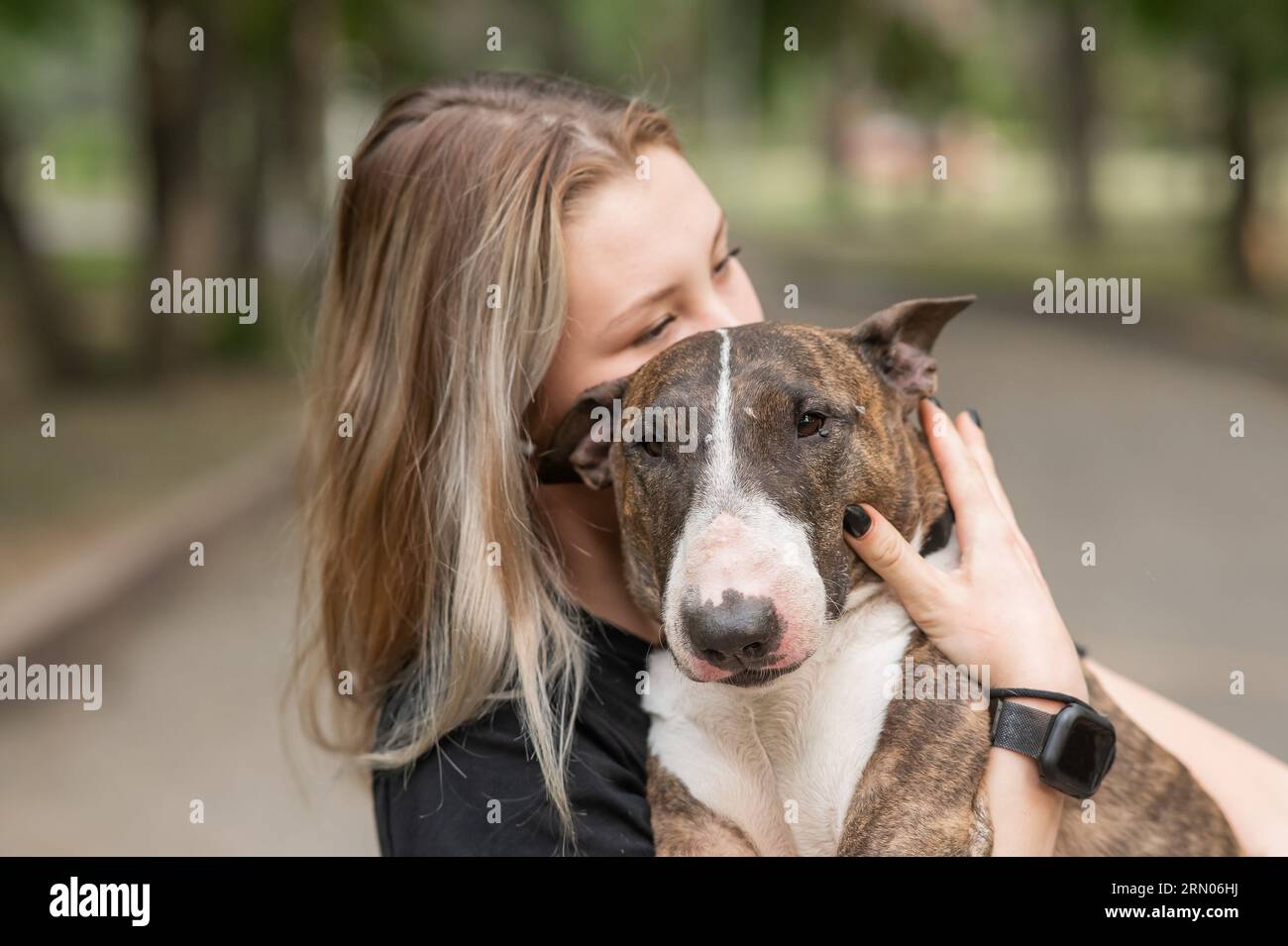 Ritratto di donna caucasica che abbraccia il suo cane Bull terrier all'aperto. Foto Stock