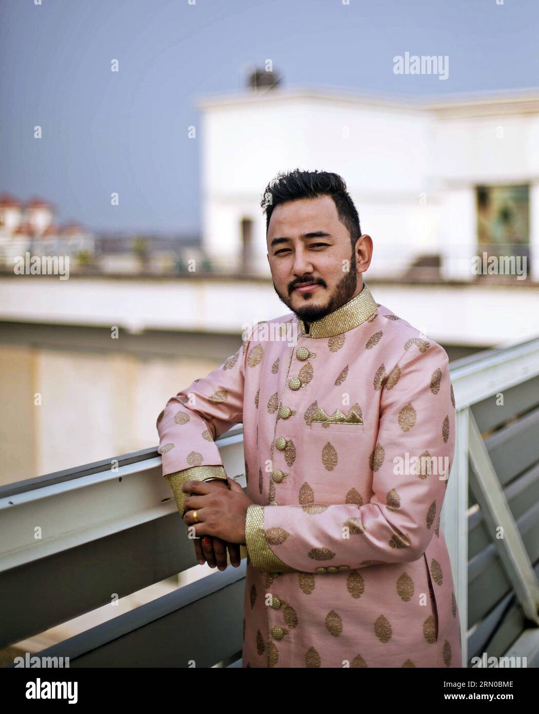 Impreziosito da un delicato sherwani rosa pallido, lo sposo nepalese, il giorno di buon auspicio del suo matrimonio, irradia eleganza e anticipazione. Foto Stock