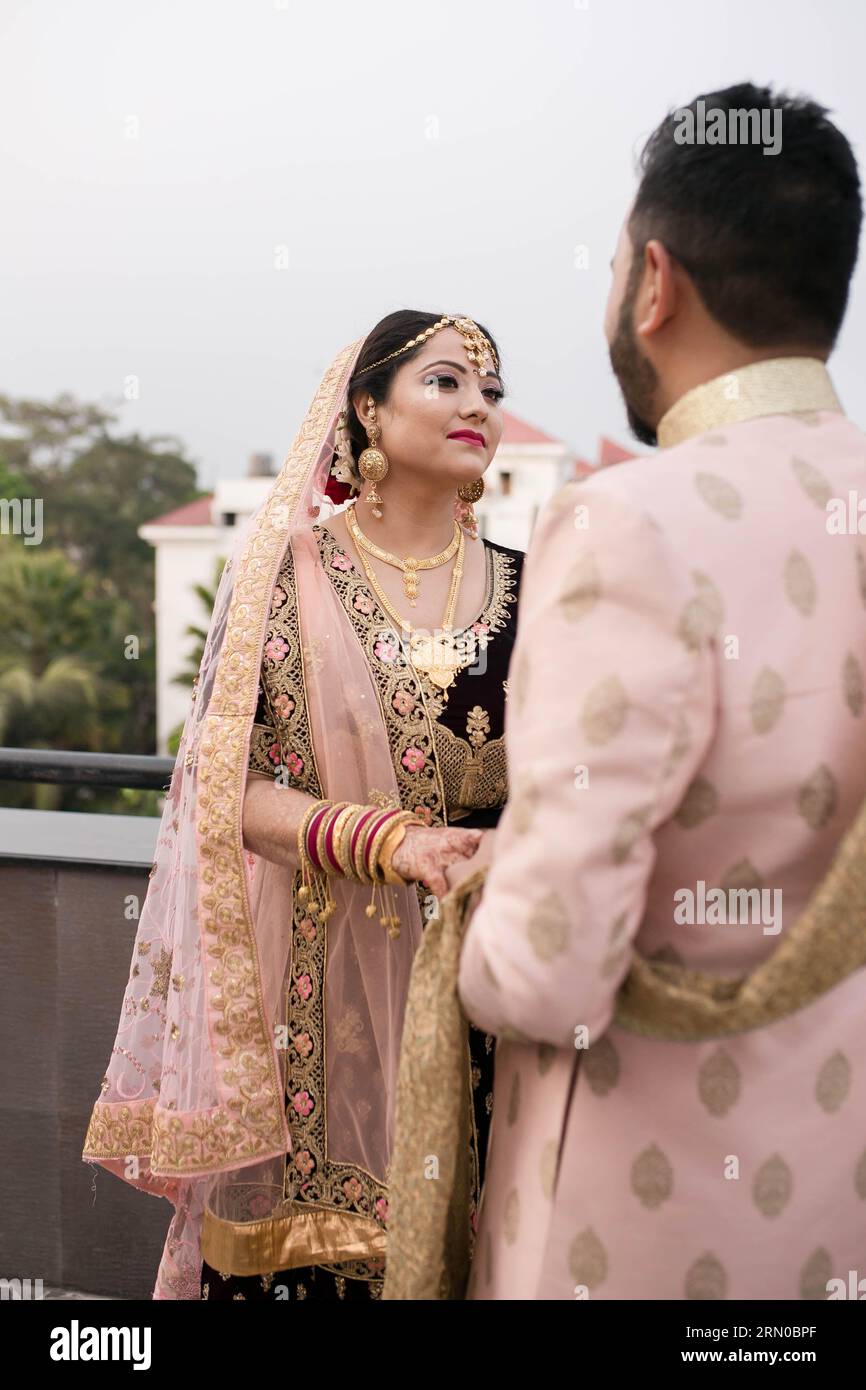 Una splendida sposa nepalese accoglie lo sposo con felicità e si guarda negli occhi, tenendosi per mano. Foto Stock
