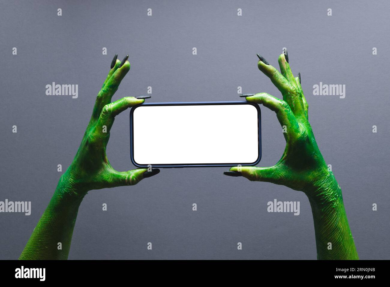 Lancette mostri verdi che tengono lo smartphone con spazio per la copia su sfondo grigio Foto Stock
