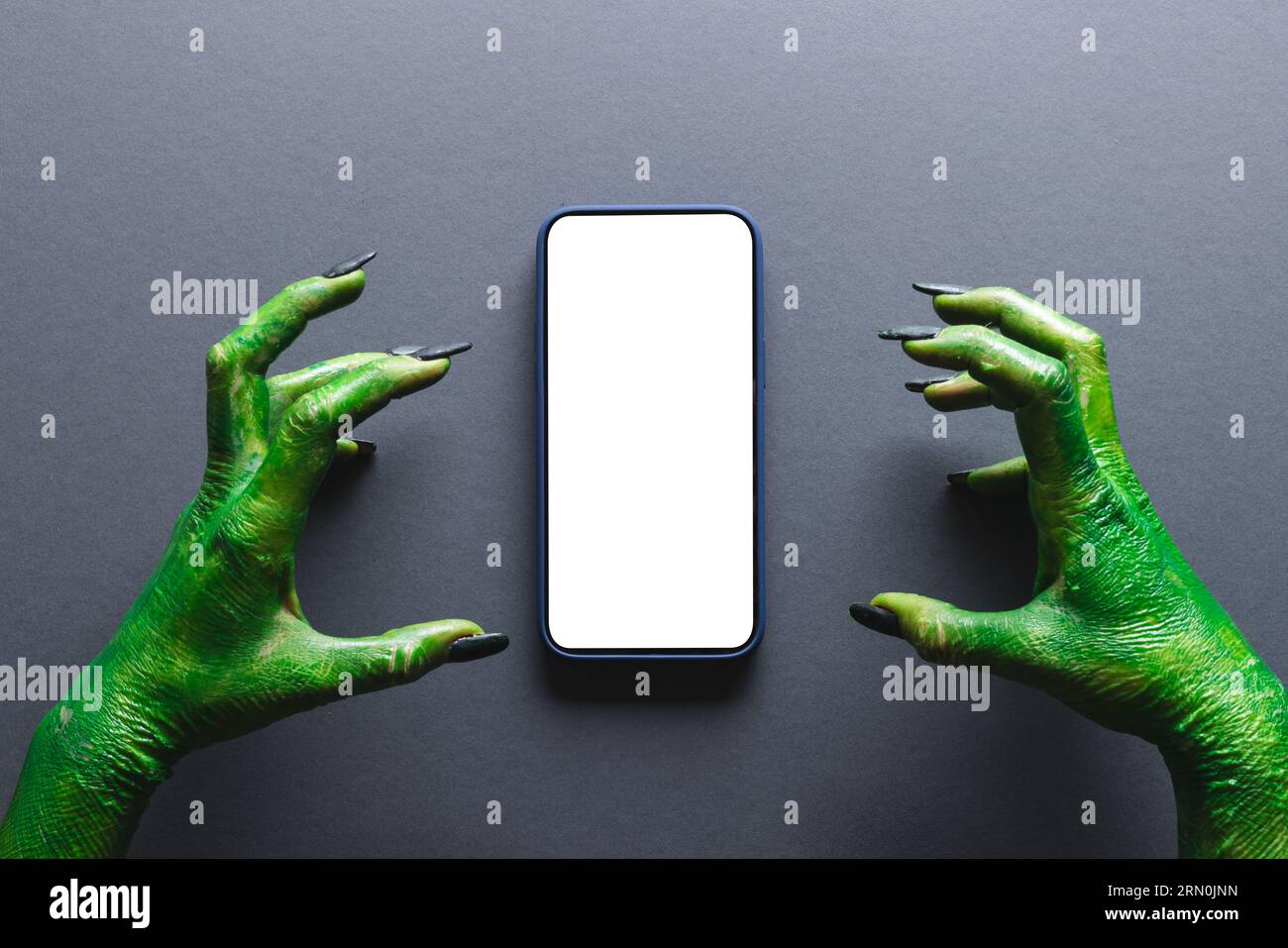 Lancette di mostri verdi che fanno gesto di tenuta sullo smartphone con spazio per la copia su sfondo grigio Foto Stock