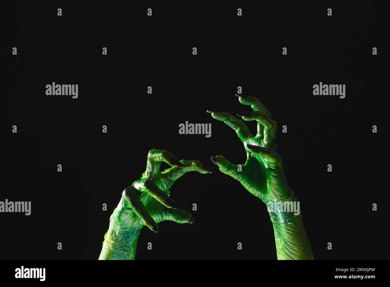 Lancette di mostro verde con unghie nere che raggiungono lo sfondo nero Foto Stock