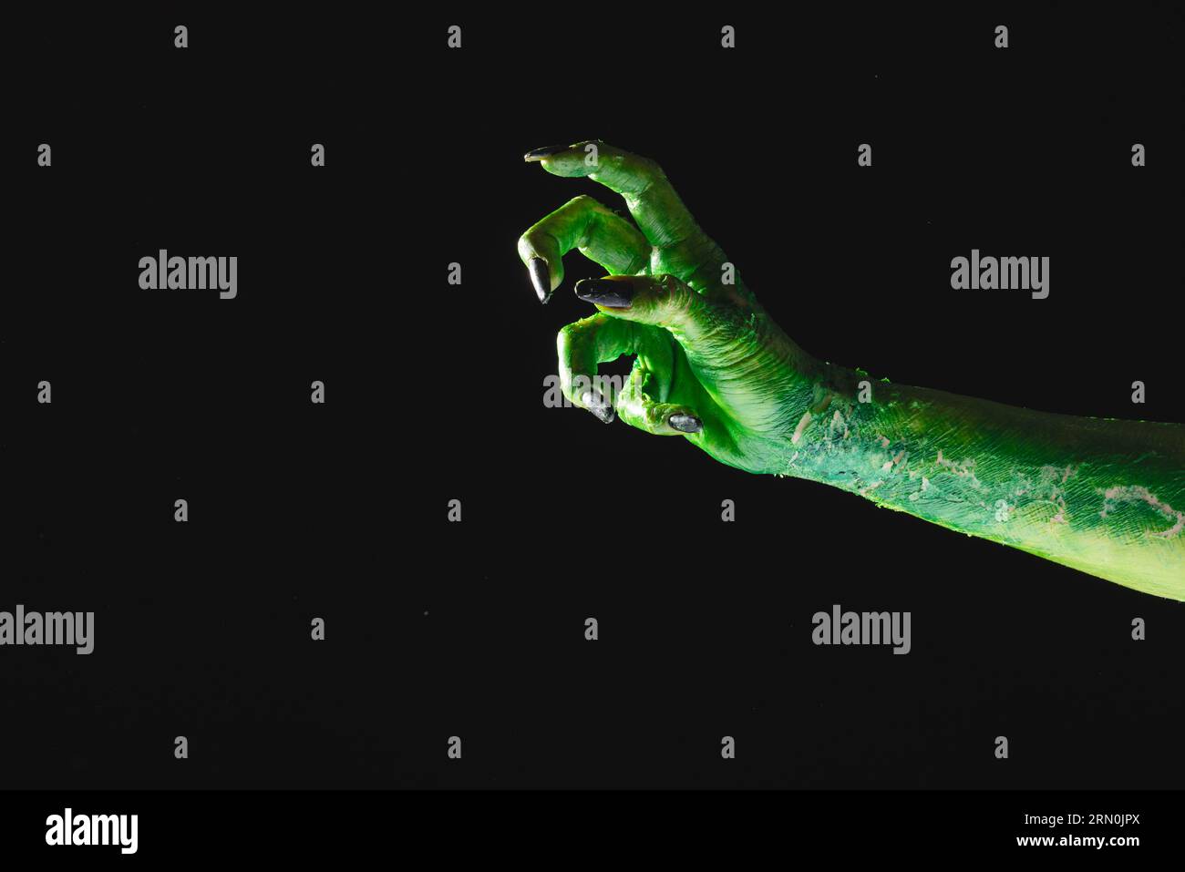 Mano mostro verde con unghie nere che raggiungono lo sfondo grigio Foto Stock