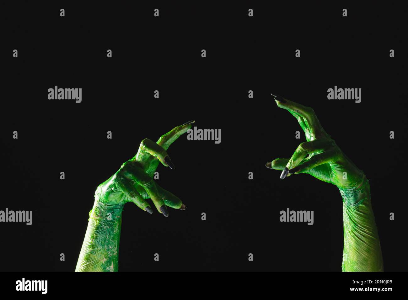 Lancette di mostro verde con unghie nere che raggiungono lo sfondo nero Foto Stock