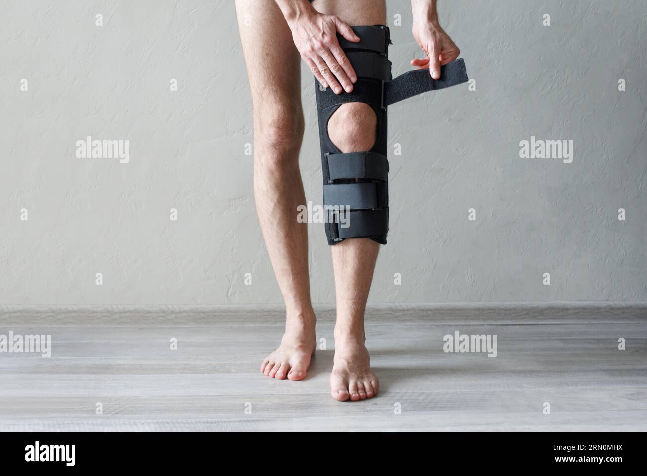 Gamba maschile con ginocchiera su sfondo grigio. Ortopedic Anatomic Orthosis (Ortopedic Anatomic Orthosis). Apparecchi per fissaggio al ginocchio, lesioni e dolore. Tutor di ortosi del piede Foto Stock