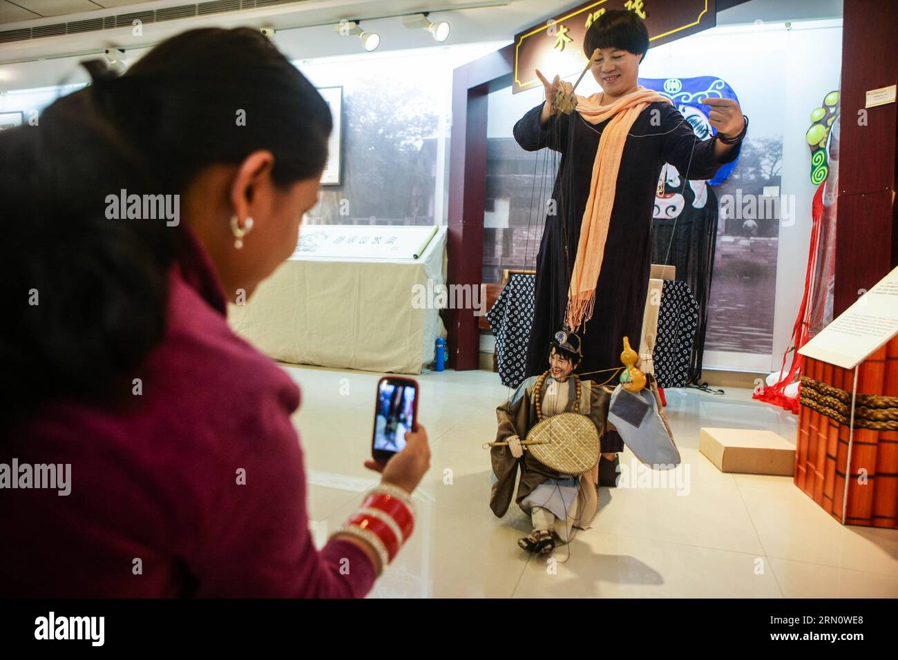 (141121) -- NUOVA DELHI, 21 novembre 2014 -- Un visitatore prende un video come Ji Tianyuan, un rappresentante erede del patrimonio culturale intangibile dello Zhejiang, esegue la marionetta Taishun alla Heavenly Creations - Exhibition on Intangible Culture Heritage of China S Zhejiang Province, nella All India fine Arts and Crafts Society di nuova Delhi, capitale dell'India, 21 novembre 2014. La mostra di cinque giorni, che ha avuto inizio qui venerdì con una selezione di tipici patrimoni della cultura immateriale di Zhejiang, mostrerà un'integrazione di mostre artistiche statiche e spettacoli dinamici. Autorizzato da ytf Foto Stock