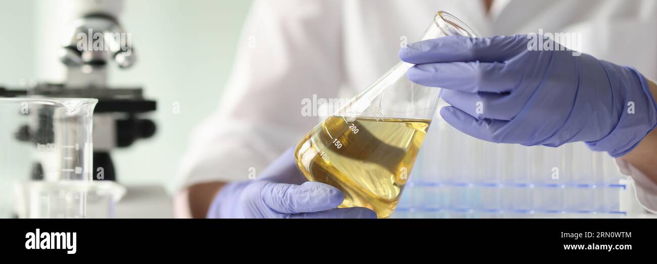 Donna scienziata in possesso di campione con liquido giallo Foto Stock
