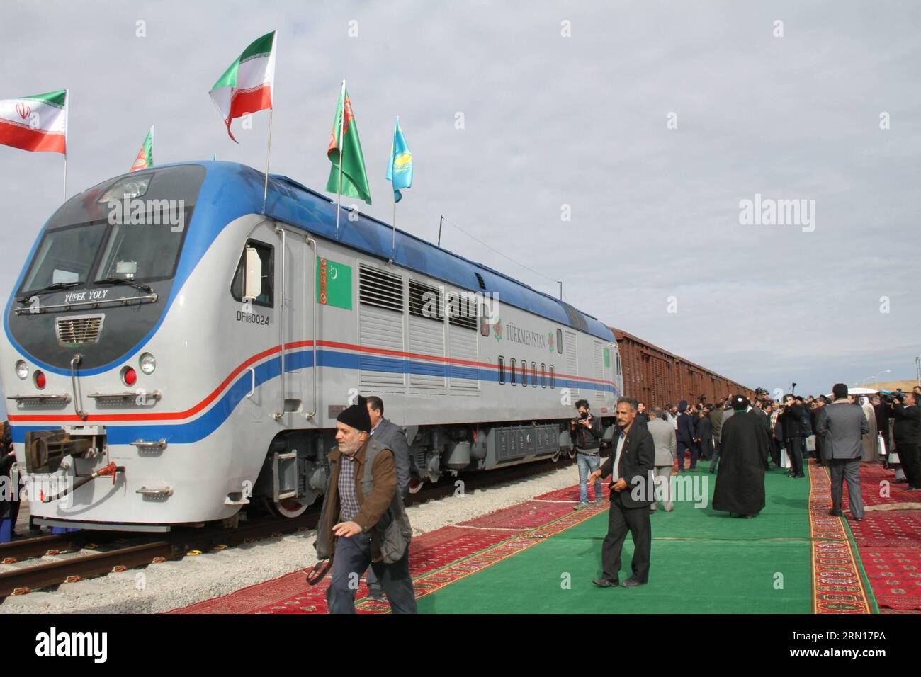 La gente si trova vicino a un treno merci prodotto in Cina durante la cerimonia di collegamento delle due sezioni della ferrovia internazionale tra Turkmenistan e Iran nel villaggio turkmeno di Ak Yayla al confine con l'Iran, il 3 dicembre 2014. Il presidente kazako Nursultan Nazarbayev, il presidente turkmeno Gurbanguly Berdimuhamedow e il presidente iraniano Hassan Rouhani hanno co-inaugurato il nuovo percorso ferroviario che migliorerà lo scambio di merci tra i tre paesi. La ferrovia è anche parte dell'arteria di trasporto dalla città costiera di Lianyungang della Cina orientale alle contee dell'Asia occidentale. )(AZP) TURKMENISTAN-AK Y Foto Stock