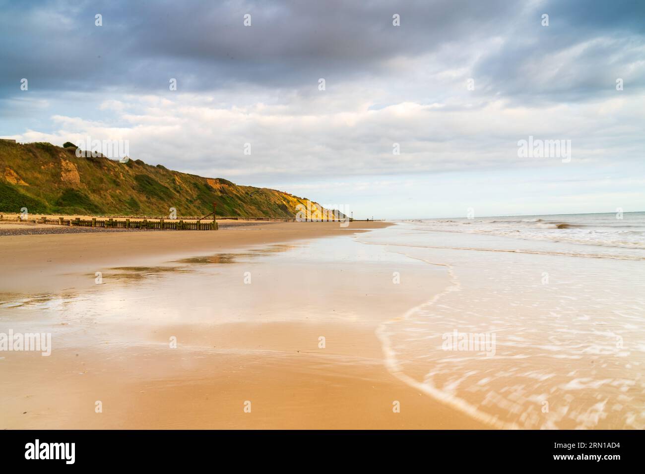 Marea che si ritira in una spiaggia vuota a Mundesley, North Norfolk Regno Unito all'alba Foto Stock