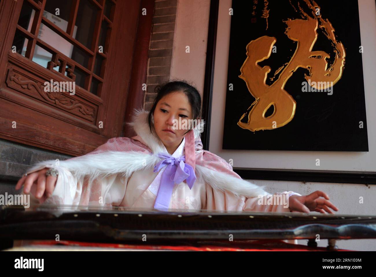 Una donna che indossa abiti cinesi Han, il costume nazionale del popolo Han in Cina, suona Guqin, uno strumento a sette corde popolare nell'antica Cina durante un rito sacrificale prima del solstizio d'inverno, o il Dongzhi Festival che cade il 22 dicembre di quest'anno, a Lanzhou, capitale della provincia del Gansu della Cina nord-occidentale, 21 dicembre 2014. Tradizionalmente, il Dongzhi Festival in Cina è un momento per la famiglia di riunirsi. ) (Yxb) CHINA-GANSU-LANZHOU-WINTER SOLSTICE (CN) ChenxBin PUBLICATIONxNOTxINxCHN una donna che indossa abbigliamento cinese Han il costume nazionale delle celebrità Han a chi Foto Stock