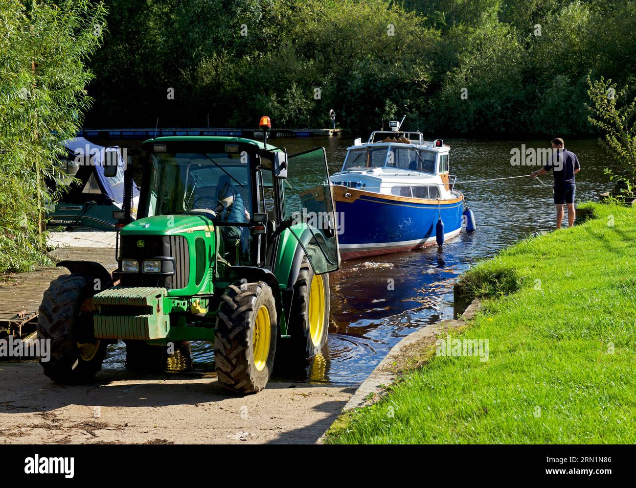 Imbarcazione in fase di lancio, con trattore, sul fiume Ouse, ad Acaster Maine, Acaster Malbis, North Yorkshire, Inghilterra, Regno Unito Foto Stock