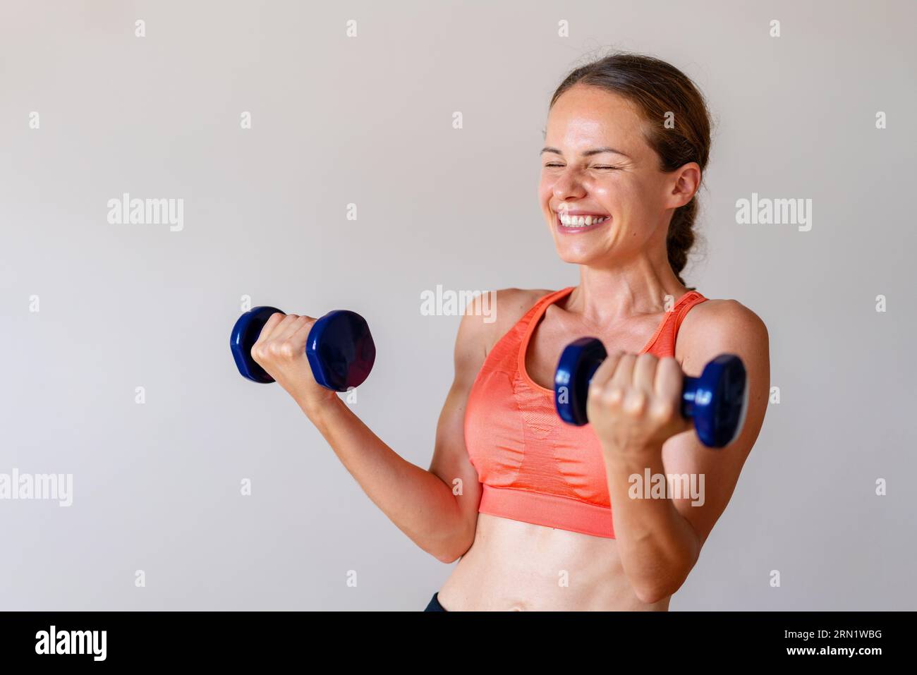 La giovane atleta si diverte facendo esercizio in palestra con i manubri. Foto Stock