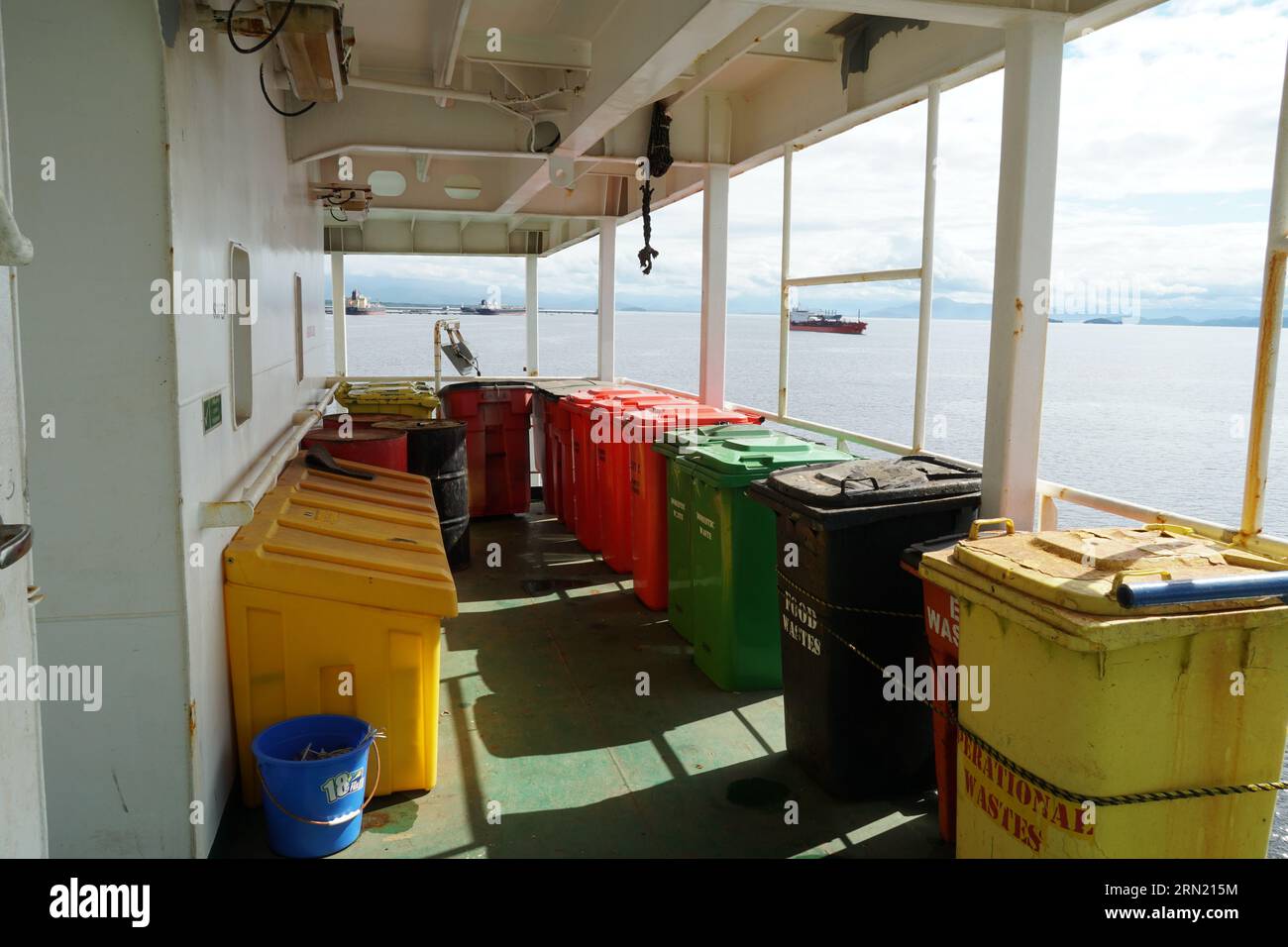 Contenitori per rifiuti in plastica di diversi colori e per rifiuti diversi, saldamente aderenti alle ringhiere. Foto Stock