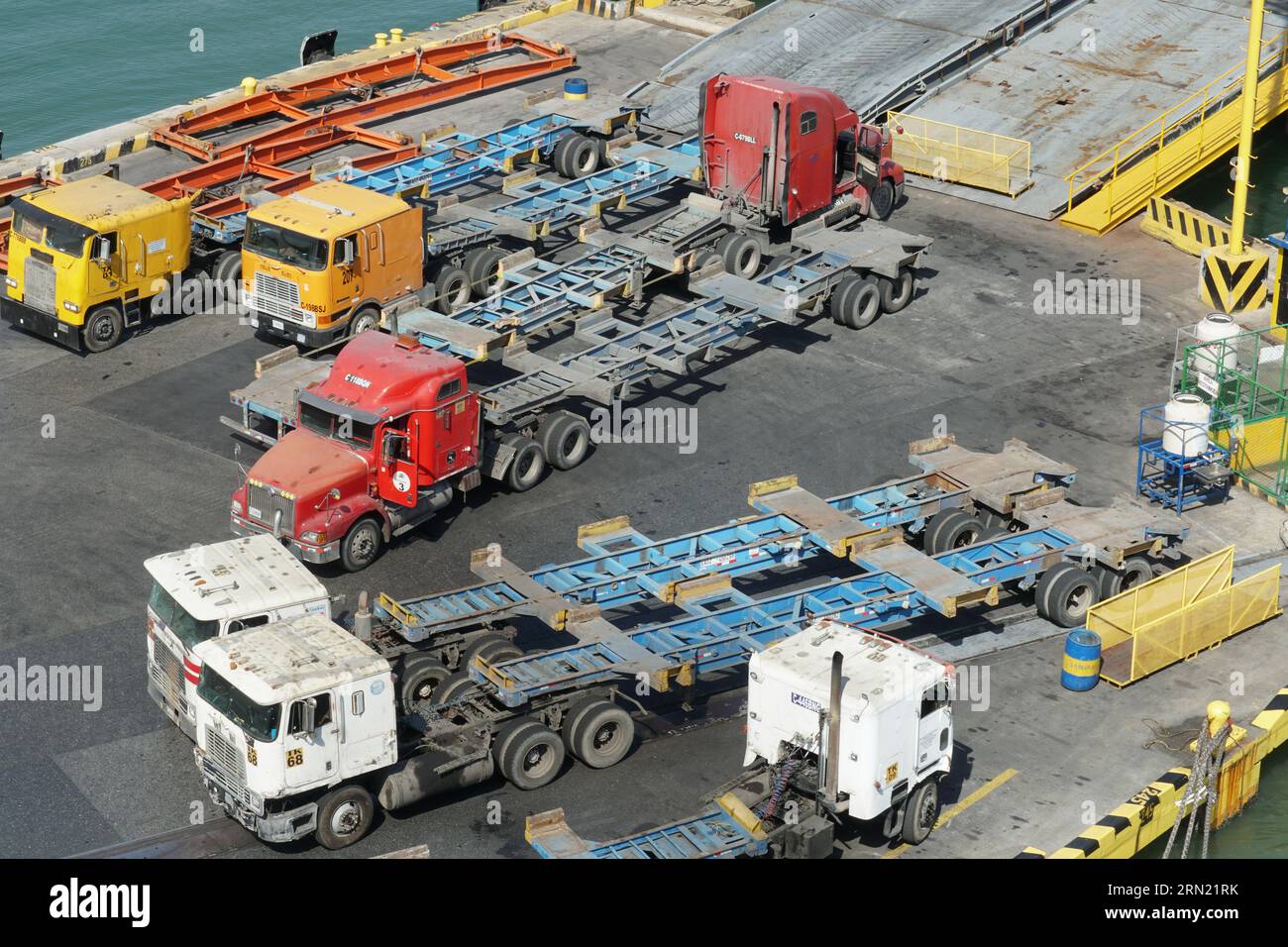 Camion e camion vuoti parcheggiati su un molo di carico accanto al pontone galleggiante come parte del terminal container di Puerto Barrios. Foto Stock