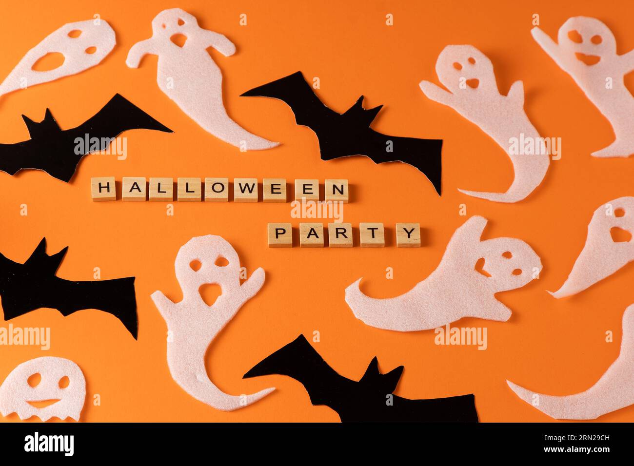 Fantasmi bianchi e mazza per la festa di Halloween. Immagine fantasma della carta di avvolgimento su sfondo arancione vista dall'alto. Fumetto Creepy Whisper. Fai-da-te fatto a mano. Impostare i caratteri boo. Parola frase di legno della lettera. Foto Stock