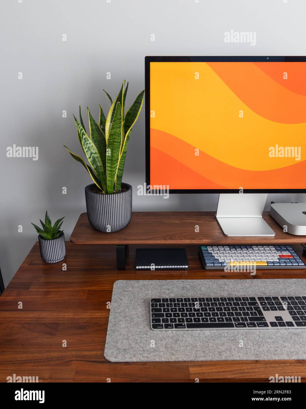 LONDRA - 24 AGOSTO 2023: Display Apple Studio e mini computer Mac in moderni impianti di home Office, lavoro da casa configurazione minima della scrivania schermo arancione Foto Stock