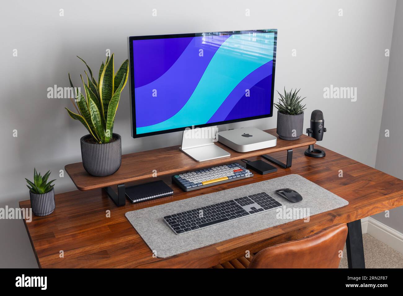 LONDRA - 24 AGOSTO 2023: Apple Studio display e Mac Mini computer in moderni impianti di home Office, lavoro da casa configurazione minima della scrivania wallp con schermo blu Foto Stock