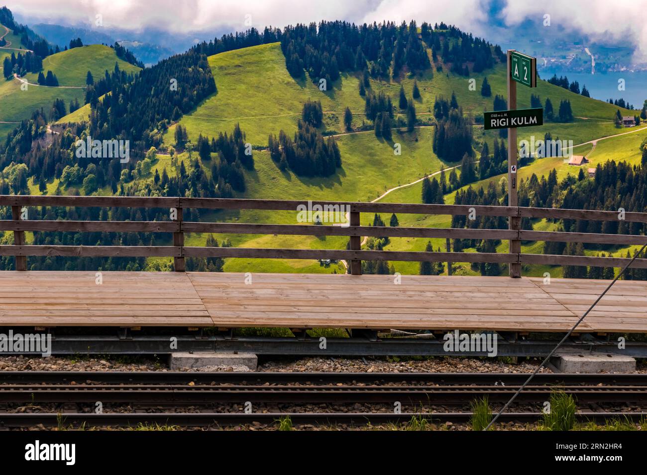 Bella vista della stazione di montagna della ferrovia a cremagliera di Rigi Kulm con un incantevole paesaggio montano sul retro. La piattaforma di legno ha un segno che... Foto Stock