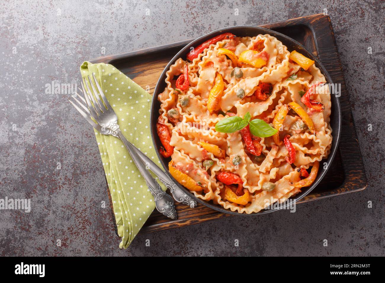 Reginette con peperoni e basilico in salsa di pomodoro cremosa con primi piani di capperi sul piatto sul tavolo. Vista superiore orizzontale dall'alto Foto Stock