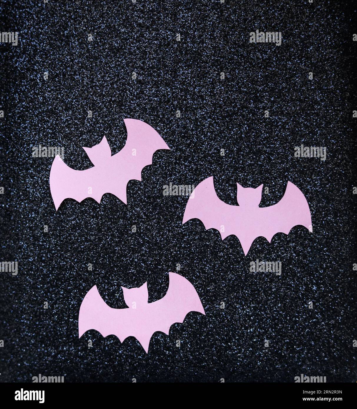 pipistrelli di carta rosa su sfondo nero glitterato concetto halloween Foto Stock