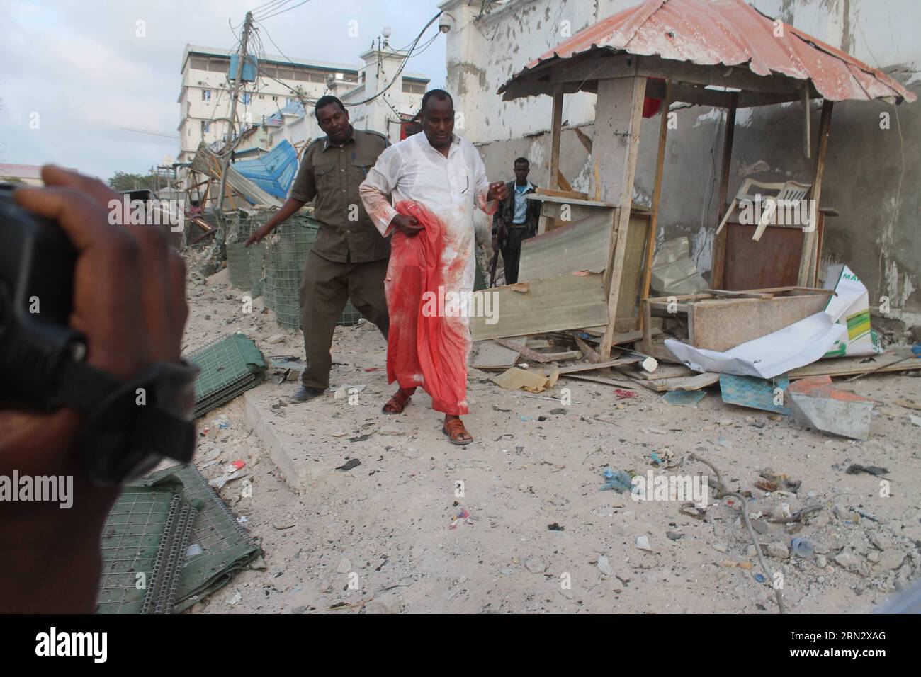Un agente di polizia aiuta un ferito a lasciare la scena di un'esplosione all'Hotel Maka al-mukarama a Mogadiscio, capitale della Somalia, il 27 marzo 2015. Almeno cinque persone sono rimaste uccise e punteggi feriti in un'esplosione di auto suicida nella capitale somala Mogadiscio venerdì, le autorità di polizia hanno confermato. ) SOMALIA-MOGADISCIO-SUICIDIO ATTACCO AbdirahmanxHussien PUBLICATIONxNOTxINxCHN a poliziotto aiuta un ferito a lasciare la scena di esplosione AL Maka al mukarama Hotel a Mogadiscio capitale della Somalia IL 27 2015 marzo almeno cinque celebrità sono state UCCISE e Scores feriti in un suicidio CA Foto Stock