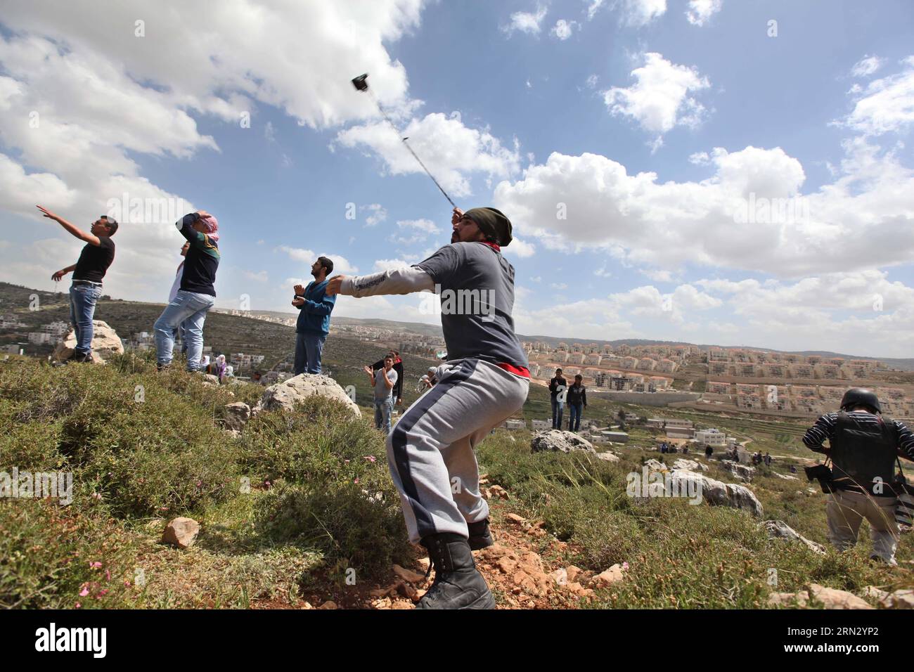 (150330) -- BETLEMME, 30 marzo 2014 -- Un manifestante palestinese lancia una pietra contro i soldati israeliani durante una protesta che segna la giornata della Terra, nel villaggio di Wadi Fukin vicino alla città di Betlemme in Cisgiordania, il prossimo marzo. 30, 2015. I palestinesi hanno celebrato la giornata della Terra il 30 marzo, la commemorazione annuale delle proteste nel 1976 contro l'appropriazione da parte di Israele di terreni di proprietà araba in Galilea. MIDEAST-BETHLEHEM-LAND-DAY-PROTESTA LuayxSababa PUBLICATIONxNOTxINxCHN Betlemme marzo 30 2014 un Hurle PALESTINESE a Stone verso i soldati israeliani durante una protesta che segna la giornata del Paese nel villaggio di Wadi vicino alla CISGIORDANIA City o Foto Stock