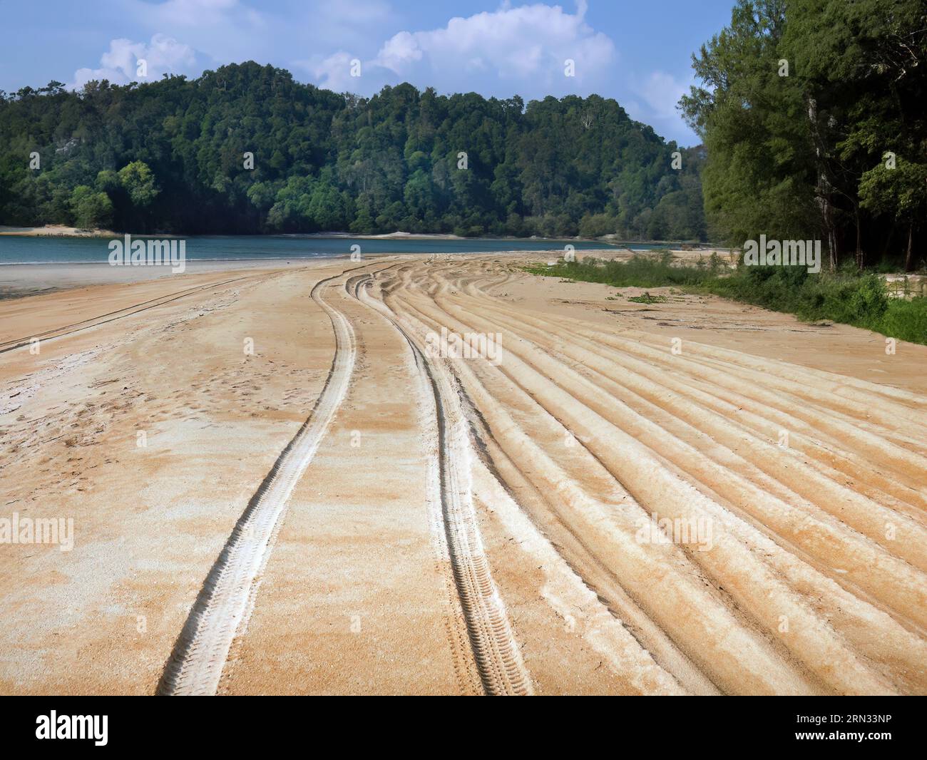 La prospettiva delle piste dei pneumatici dei veicoli 4x4 è stata vista sulla sabbia dorata, le jeep hanno guidato lungo l'ampia spiaggia sabbiosa, il mare delle Andamane, le verdi montagne e il cielo blu i. Foto Stock