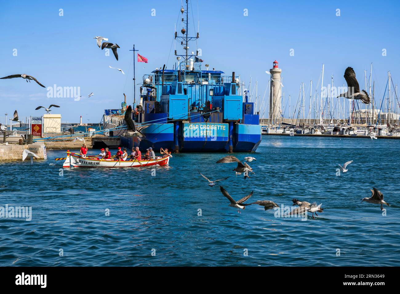 Francia, Herault, Sete, porto di pesca, imbarcazione dell'associazione Occitarame che si batte per la pratica del canottaggio tradizionale, il faro di Saint-Louis sullo sfondo Foto Stock