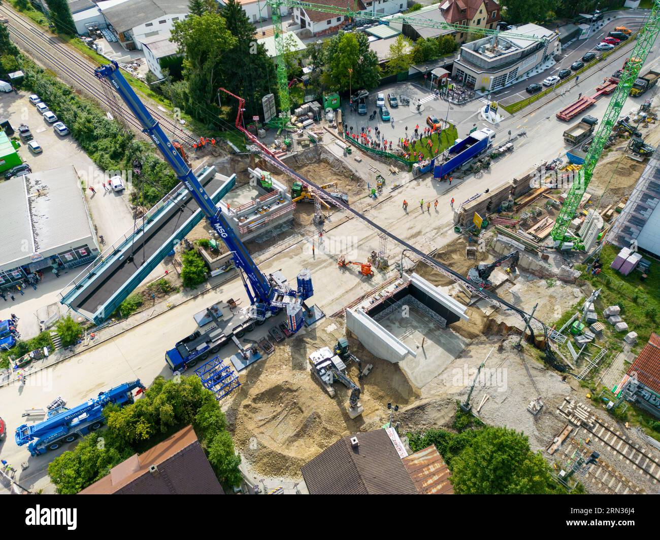 Starnberg, Germania. 31 agosto 2023. Una gru solleva un nuovo cavalcavia ferroviario sull'autostrada federale 2 a Starnberg fino alla sua fondazione. (Foto aerea scattata con un drone) il nuovo ponte avrà un'altezza di 4,5 metri e una larghezza di 26,3 metri. Due sovrastrutture in acciaio, ognuna del peso di 120 tonnellate, sono state sollevate nella loro posizione finale da una gru blu montata su autocarro da 650 tonnellate. Crediti: Peter Kneffel/dpa/Alamy Live News Foto Stock