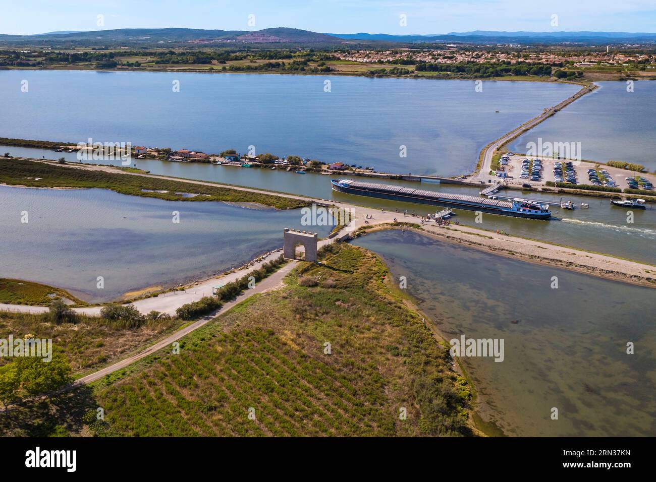 Francia, Hérault (34), Villeneuve-lès-Maguelone (Palavas-Les-Flots), péniche sur le Canal du Rhône à Sète passant la Passerelle du Pilou devant la porte de Maguelone sur l'Ile de Maguelone, Villeneuve-lès-Maguelone en arrière plan (vue aérienne)/Francia, Herault, Villeneuve les Maguelone (Palavelone), Les Faguelone), Les Faguelone (Palavelone) chiatta sul Rodano fino al Canale di Sète passando per la Passerelle du Pilou di fronte alla porte de Maguelone sull'Ile de Maguelone, Villeneuve les Maguelone sullo sfondo (vista aerea) Foto Stock