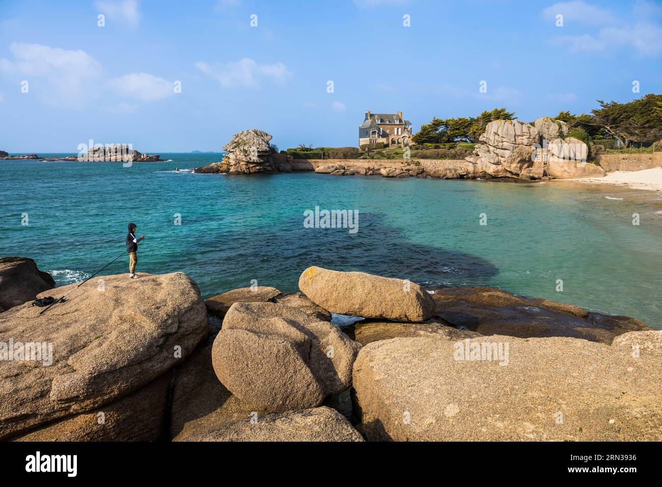 Francia, Cotes-d'Armor, Cote de Granit Rose, Trégastel, giovane pescatore sulle rocce di fronte alla spiaggia di Ker ar Vir lungo il sentiero escursionistico GR 34 Foto Stock