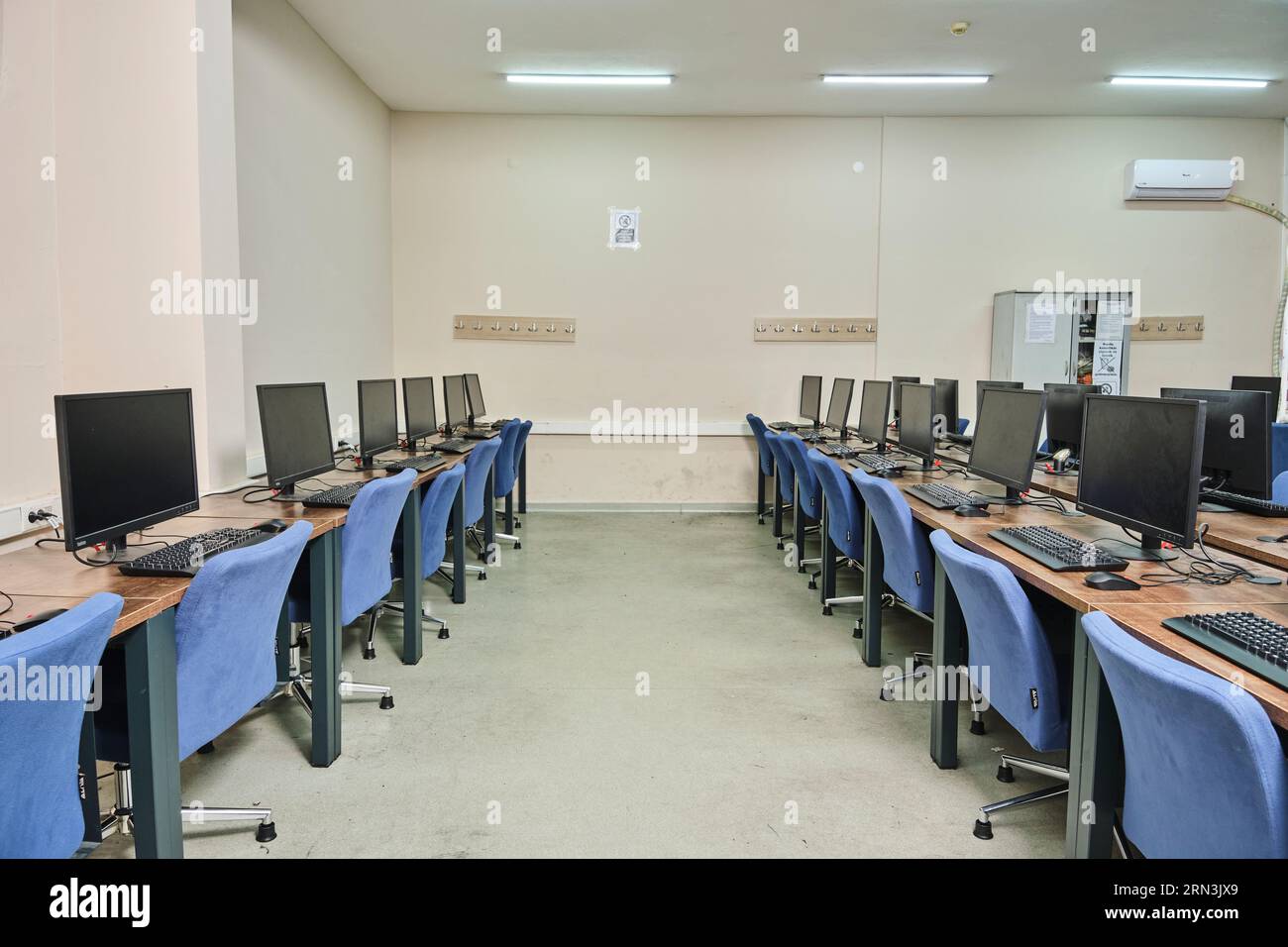 un laboratorio informatico vuoto in un'università. Sala di laboratorio per computer. camera con molti computer, scrivanie, sedie e tastiere. Foto Stock